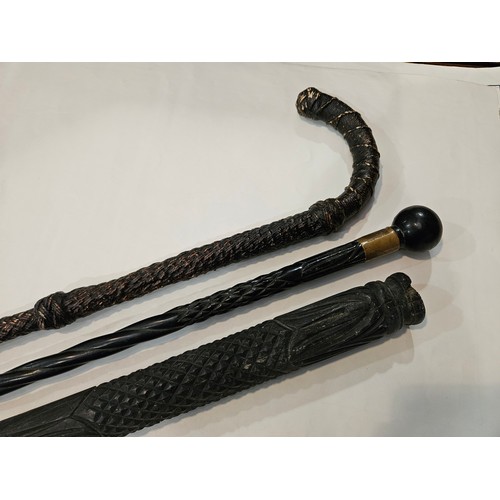 4012 - A heavy carved ebony walking stick (missing pommel and tip), slender ebony walking cane and another ... 