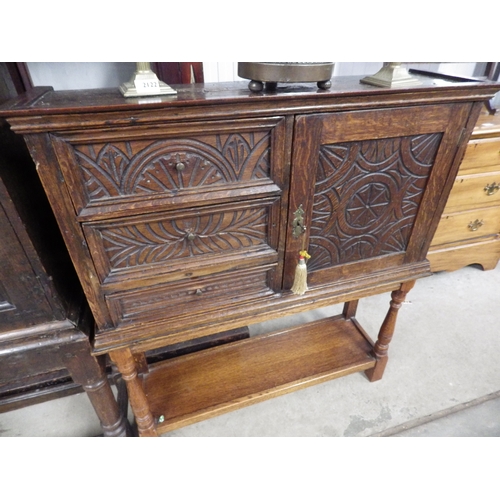 2124 - A carved oak three drawer one door cabinet on stand