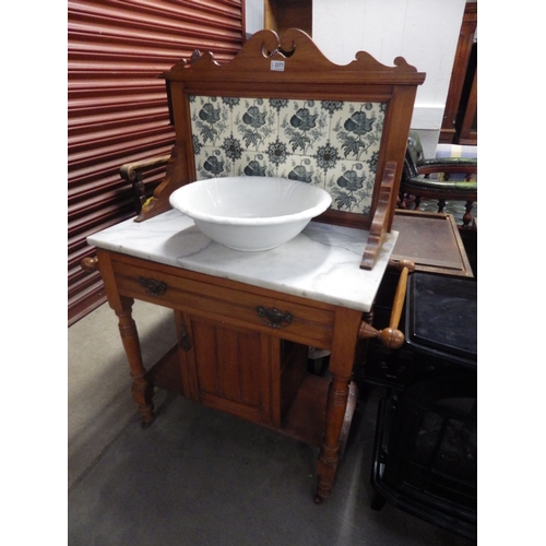 2377 - A marble top washstand with cupboard base and tiled back, on castors