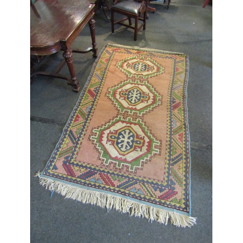 1481 - A peach and cream ground geometric design rug, three central lozenges, multiple borders and tasselle... 