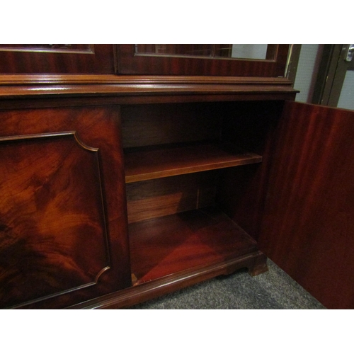 1032 - A George III style flame mahogany two door glazed bookcase over a two door cupboard on outswept brac... 
