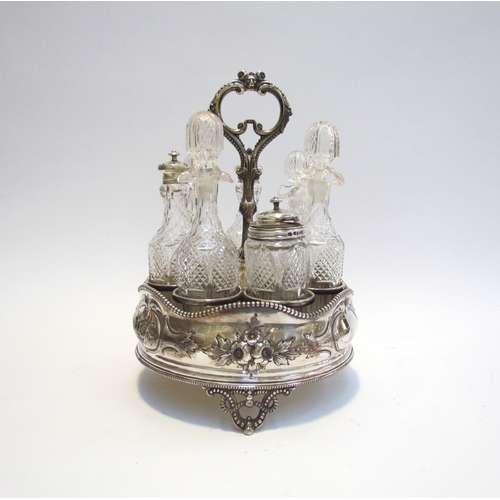 4387 - A Victorian silver plate cruet stand with swivel 7 bottle container, 3 with silver lids. Floral embo... 