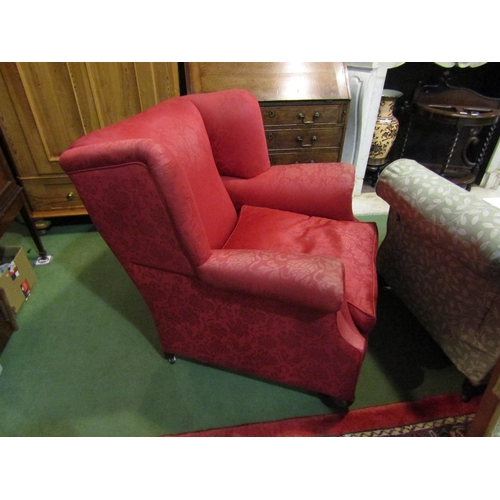 4184 - A Circa 1920 wing back club armchair with red upholstery on bun fore feet and castors