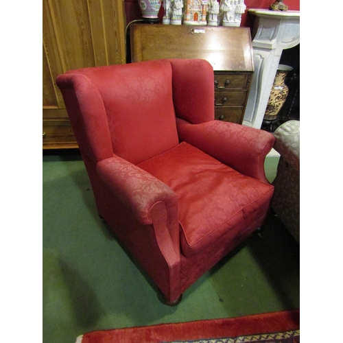 4184 - A Circa 1920 wing back club armchair with red upholstery on bun fore feet and castors