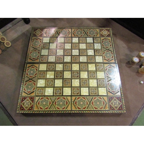 4228 - A folding Eastern inlaid backgammon board with inlaid counters and dice, open 50cm x 50cm