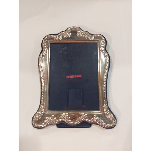 4372 - A silver photograph frame with embossed floral decorated shaped edge, easel back. Hallmarked 1998 ma... 