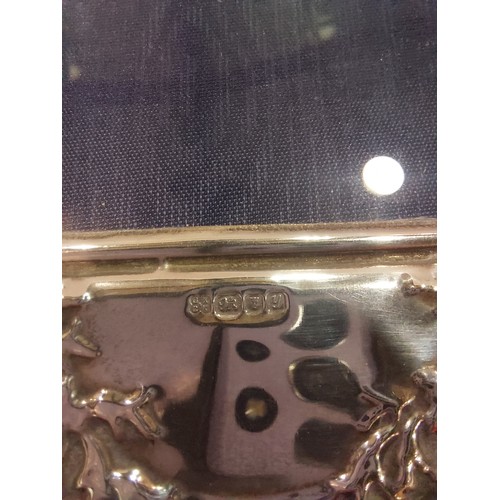 4372 - A silver photograph frame with embossed floral decorated shaped edge, easel back. Hallmarked 1998 ma... 