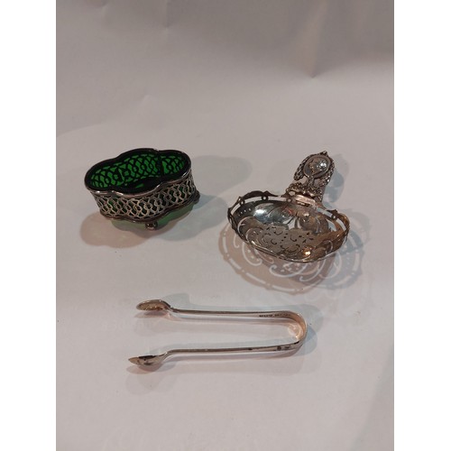 4381 - A pierced silver salt with green glass liner, sugar tongs and a Continental silver strainer (3)