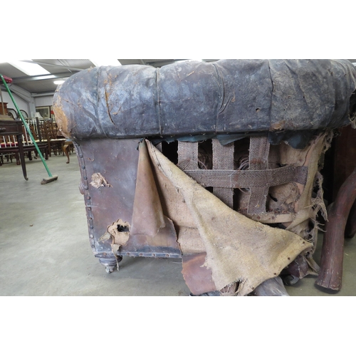 2001 - A Victorian well worn leather sofa on three turned front legs for restoration