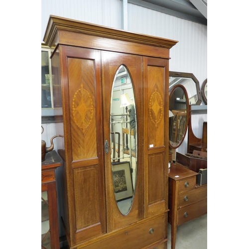 2100 - An Edwardian mahogany wardrobe, oval mirrored door single drawer base