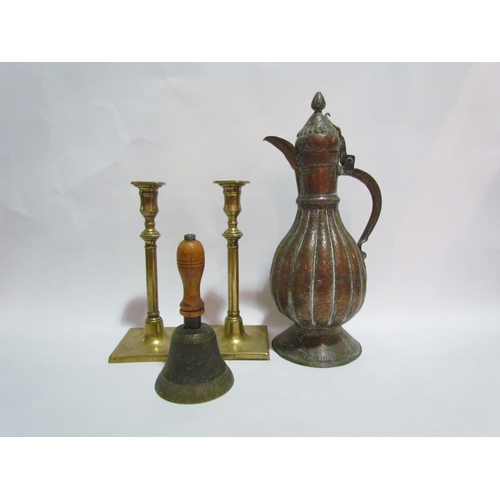 4335 - A Persian copper coffee pot together with a pair of slender candlesticks and a hand bell (4)