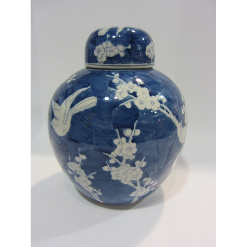 4445 - A blue and white ginger jar decorated with birds and prunus, approximately 26cm tall