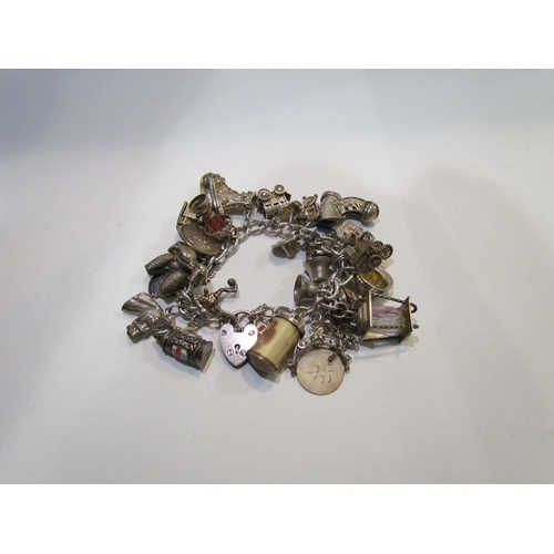 4416 - A heavy silver charm bracelet with approx. 30 various charms including dogs, skates, horse, car etc.... 