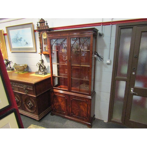 1036 - A George III style flame mahogany two door glazed bookcase over a two door cupboard on outswept brac... 