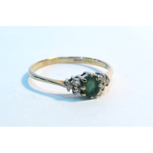 1263 - A 9ct gold emerald and diamond ring the central oval emerald flanked by three diamonds. Size P, 1.3g