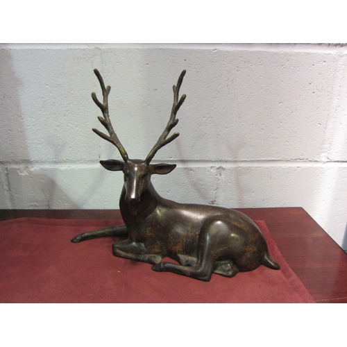 1133 - A bronzed metal figure of a recumbent stag, 27.5cm tall