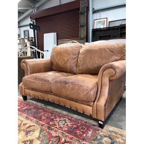 2258 - A nicely worn tan leather two seater cottage sofa