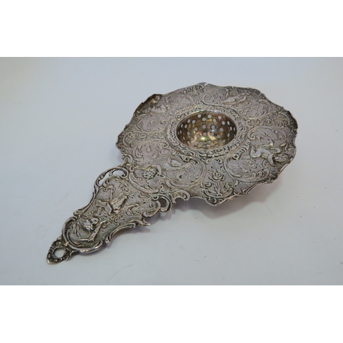 1219 - A Berthold Muller silver tea strainer with embossed putti design, 15cm long, 55g