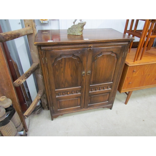 2307 - A dark oak two door cupboard with arched panels and spindle detail