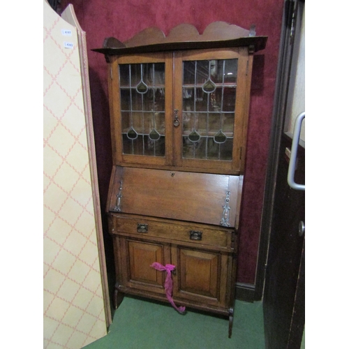 4199 - An Arts and Crafts oak bureau bookcase, the lead glazed two door top over a fall front to a drawer a... 