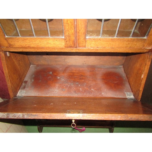 4199 - An Arts and Crafts oak bureau bookcase, the lead glazed two door top over a fall front to a drawer a... 