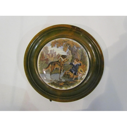 4351 - A Pratt Ware pot lid depicting boy sitting by stream, dog with yacht in his mouth, wooden frame, 17.... 