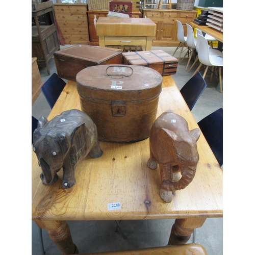 2207 - A vintage scumbled tin hat box together with two hardwood carved elephants (3)