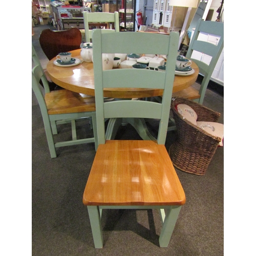 1106 - An oak kitchen table and four chairs, the natural circular top over green painted base, 76cm tall x ... 