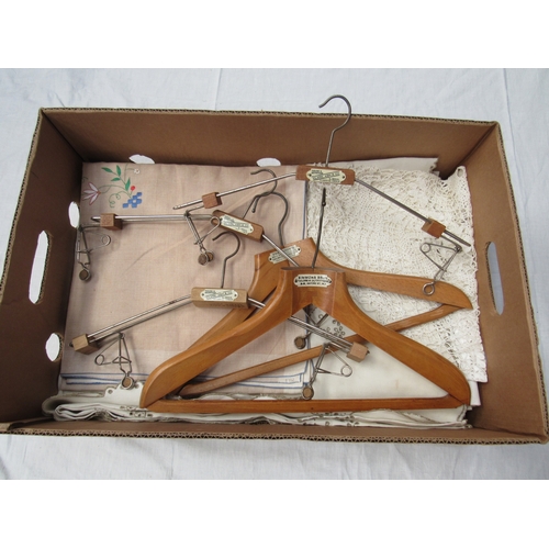 8035 - A box containing vintage table linens, huckaback towels and five vintage wooden coat hangers bearing... 