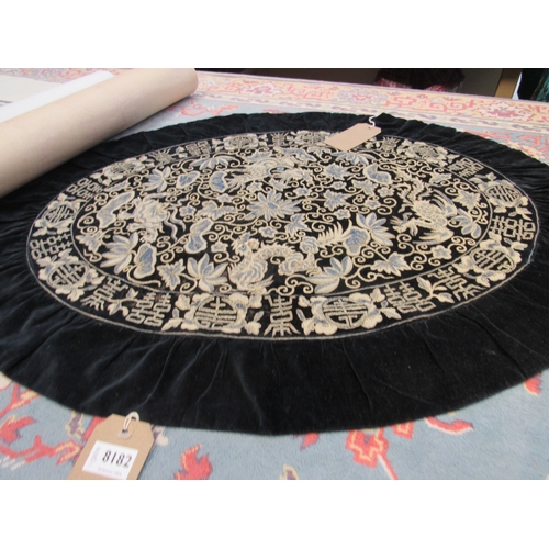 8182 - An oval velvet backed heavily embroidered Oriental table cover depicting dragons bordered by symbols