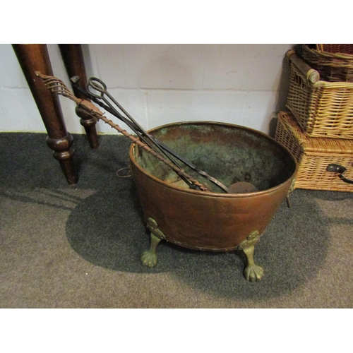 1042 - A copper and brass coal basket on paw feet with lion mask handles together with three fireside tools