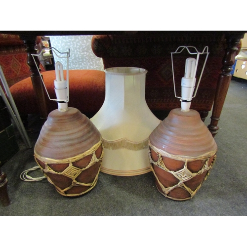 1158 - Two terracotta table lamps wrapped with reed decoration, 57cm overall height