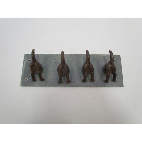 1303 - A set of dog tail coat hooks on slate surround, 30cm long