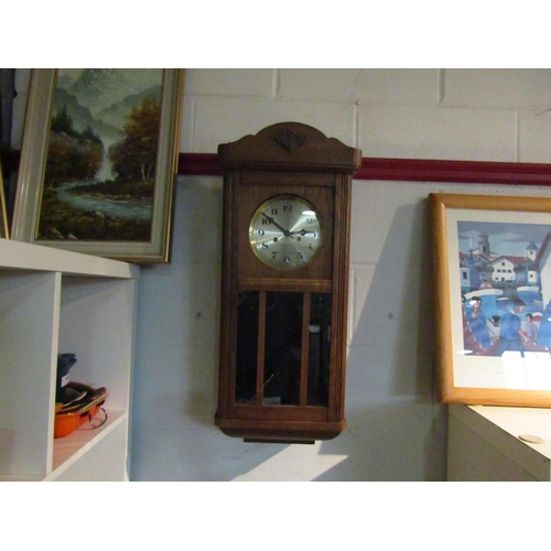 1424 - An early 20th Century wall clock with silvered face and Arabic numerals, with key and pendulum