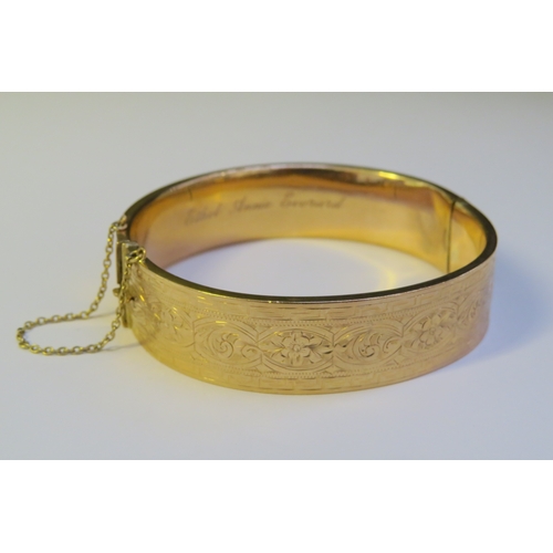 9193 - A 9ct gold stiff hinge bangle, with engraved decoration, dented, 20g  (C)