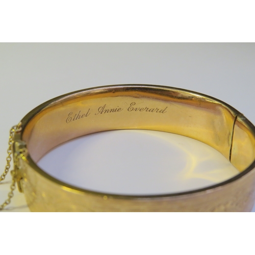 9193 - A 9ct gold stiff hinge bangle, with engraved decoration, dented, 20g  (C)