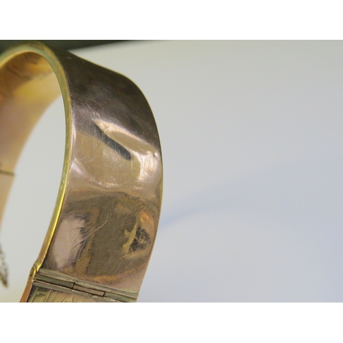 9193 - A 9ct gold stiff hinge bangle, with engraved decoration, dented, 20g  (C)