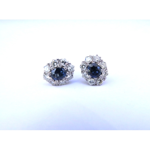 9268 - A pair of sapphire and diamond cluster earrings, the centre oval sapphire 6mm x 5mm, framed by eight... 