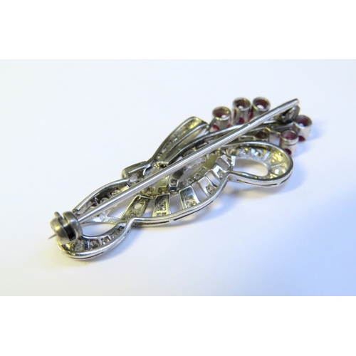 9153 - A diamond and ruby encrusted brooch as a floral sprig, with brilliant and baguette cut diamonds, 4.5... 