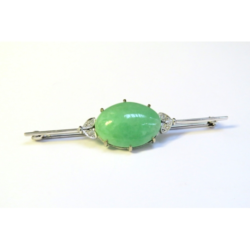 9301 - A white gold bar brooch set centrally with a jade cabochon flanked by two diamond set leaves, stampe... 