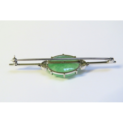 9301 - A white gold bar brooch set centrally with a jade cabochon flanked by two diamond set leaves, stampe... 