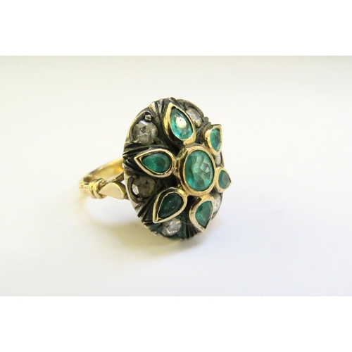 9257 - A diamond and emerald ring, the central oval emerald framed by six pear shaped emeralds spaced by ol... 