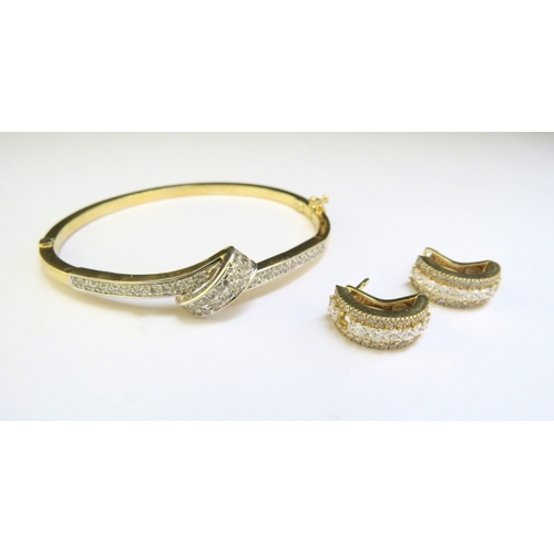 9320 - A stiff hinged bangle set with clear stones stamped 585 with a pair of matching earrings, one stone ... 