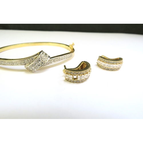 9320 - A stiff hinged bangle set with clear stones stamped 585 with a pair of matching earrings, one stone ... 