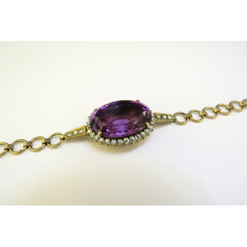 9343 - A bracelet centrally set with an oval amethyst framed by clear stones, unmarked, 16.5cm long