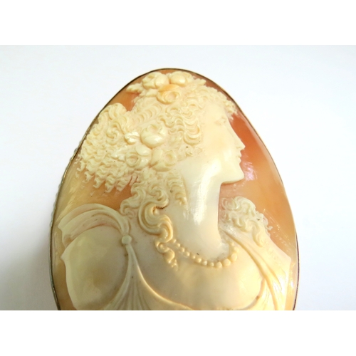 9081 - A large finely carved shell cameo brooch depicting young woman with ringlets, wearing flowers in her... 