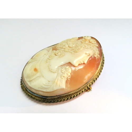 9081 - A large finely carved shell cameo brooch depicting young woman with ringlets, wearing flowers in her... 