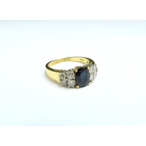 9109 - An 18ct gold ring with oval sapphire flanked by four diamonds. Size P, 5.6g  (C)