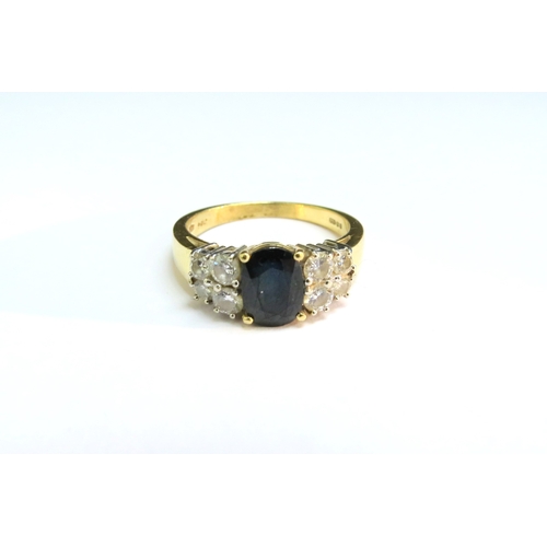 9109 - An 18ct gold ring with oval sapphire flanked by four diamonds. Size P, 5.6g  (C)