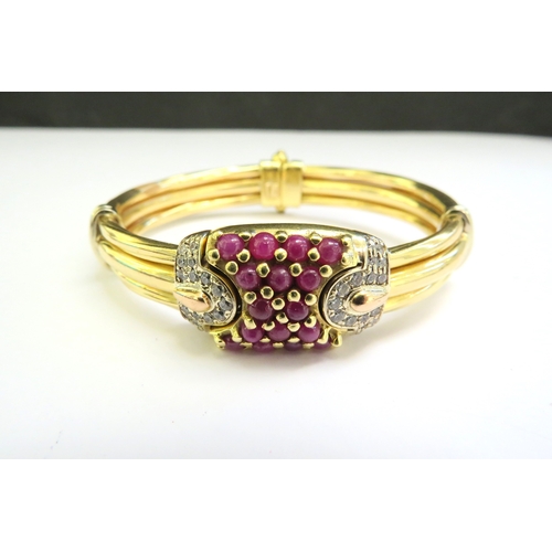 9059 - A gold sprung bangle with a cabochon ruby studded centre flanked by diamonds, stamped 750, 38.6g  (C... 